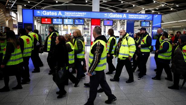 Members of Germany's union Verdi wear yellow vests as they march in front of Gate A of Duesseldorf Airport during a strike