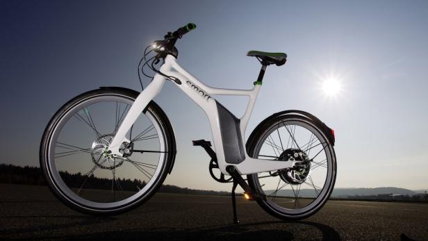 Ein weißes Smart E-Bike steht auf einer asphaltierten Fläche.