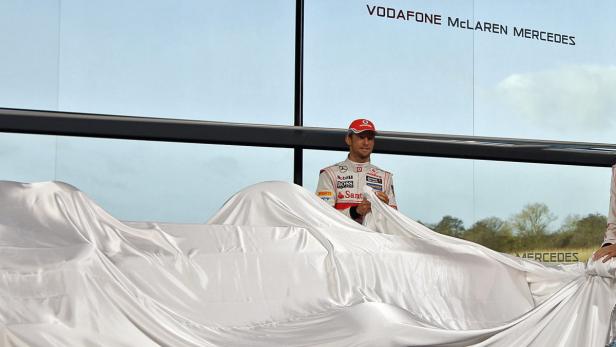 Ein Rennfahrer von Vodafone McLaren Mercedes enthüllt ein neues Auto, das mit einem weißen Tuch bedeckt ist.
