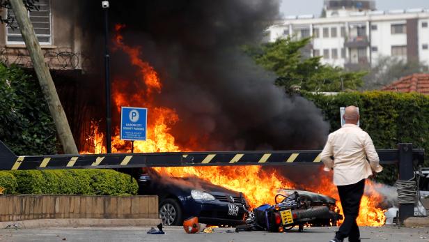 Cars are seen on fire at the scene where explosions and gunshots were heard at the Dusit hotel compound, in Nairobi