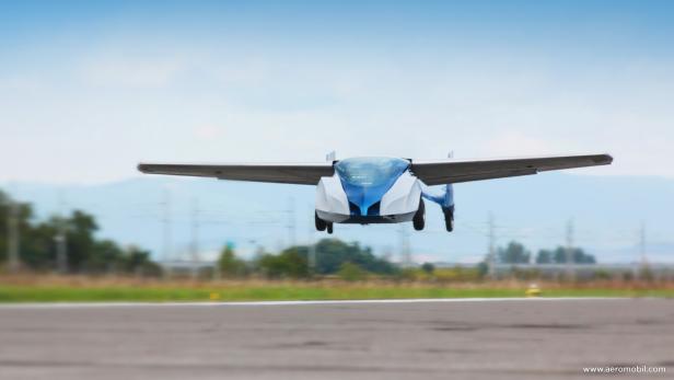 Ein fliegendes Auto, möglicherweise ein Prototyp, hebt von einer Landebahn ab.
