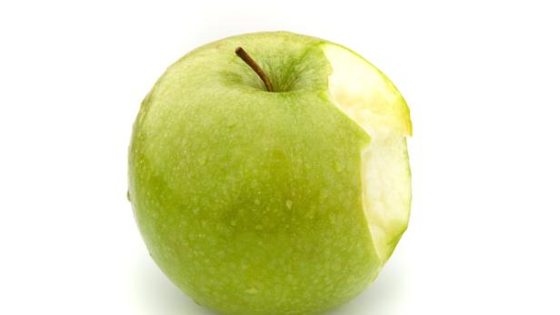 Ein angebissener, grüner Apfel liegt auf einem weißen Hintergrund.