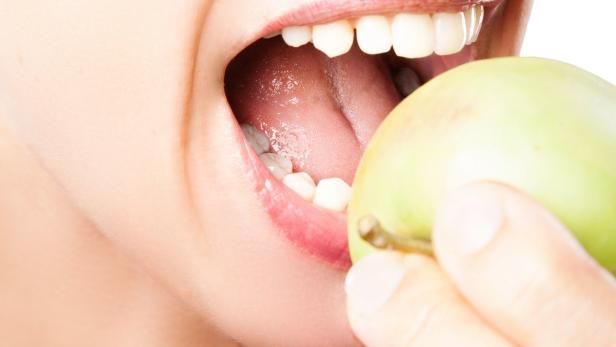 Mund mit gesunden Zähnen beißt in grünen Apfel