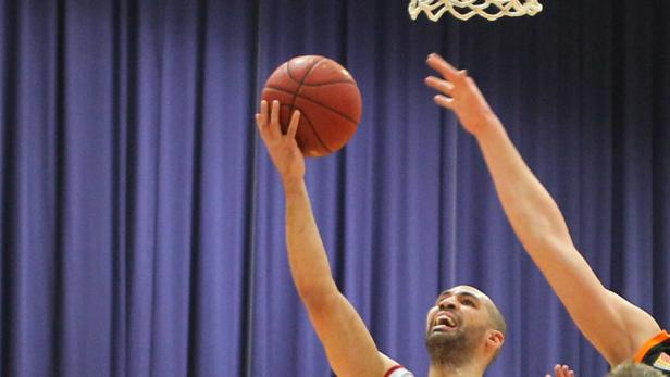 Ein Basketballspieler wirft den Ball in Richtung Korb.