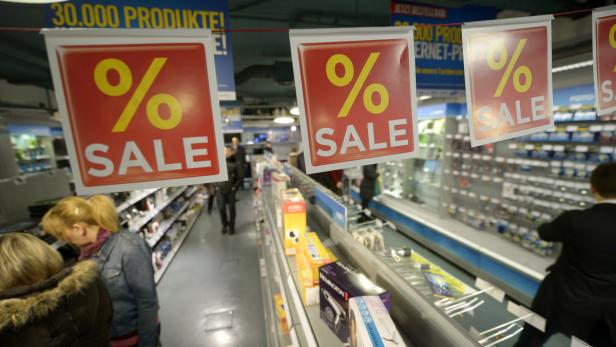 Kunden beim Einkaufen in einem Geschäft mit „Sale“-Schildern.