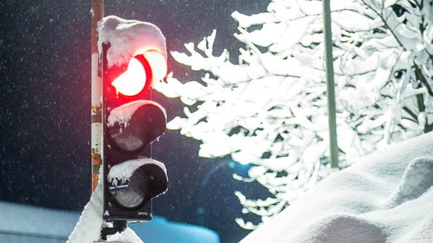 Eine rote Ampel ist von Schnee bedeckt.