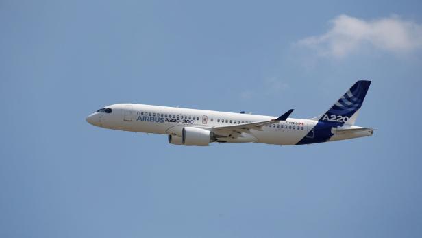 Ein Airbus A220-300 Flugzeug fliegt vor einem blauen Himmel.