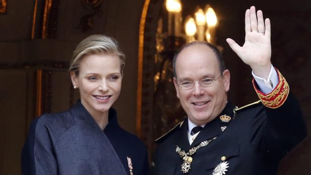 Fürst Albert II. von Monaco und seine Frau Charlène lächeln und winken.