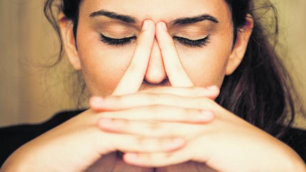 Nahaufnahme einer müden, jungen Frau, die ihre Nase reibt.