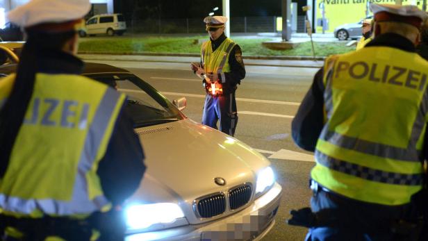 Polizisten kontrollieren ein Auto bei Nacht.