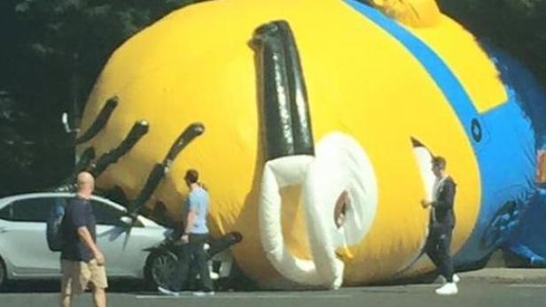 Ein riesiger, gelber Minion-Luftballon liegt auf einer Straße.