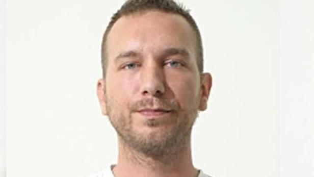 Porträt eines Mannes mit Bart und hellen Augen vor einem weißen Hintergrund.