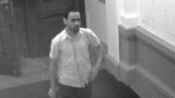 Ein Mann mit Bart steht in einem Flur.