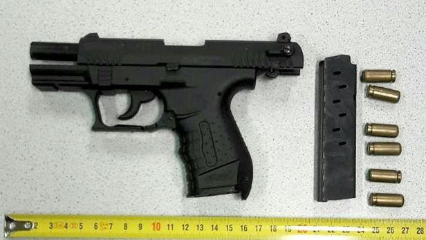 Eine schwarze Pistole liegt neben einem Magazin und mehreren Patronen auf einem Tisch.
