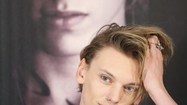 Jamie Campbell Bower posiert vor einem Porträt von sich selbst.