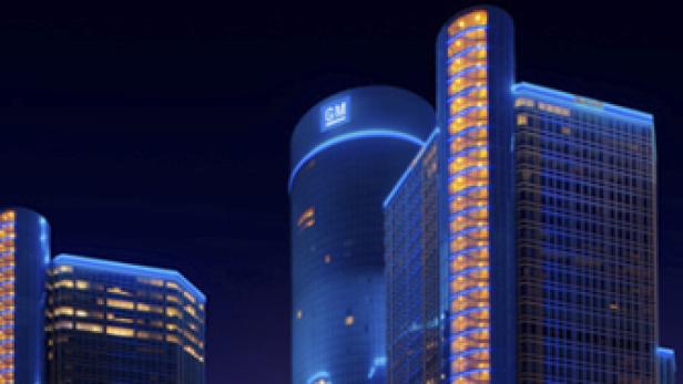 Das General Motors Renaissance Center in Detroit bei Nacht, beleuchtet in Blau und Orange.