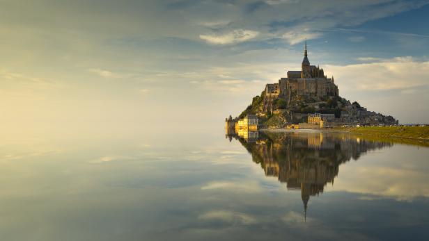 Der Mont-Saint-Michel spiegelt sich im ruhigen Wasser.