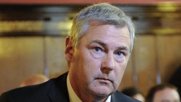 Porträt eines Mannes mit grauen Haaren und blauen Augen.