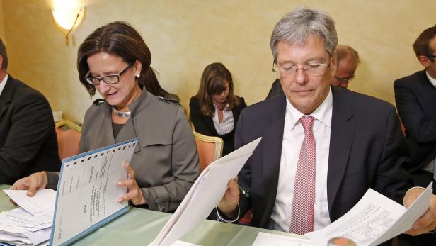 Eine Frau und ein Mann sitzen an einem Tisch und betrachten Dokumente.