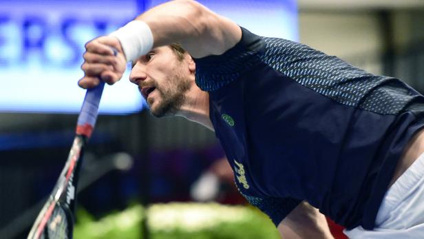 Ein Squashspieler schlägt den Ball mit seinem Schläger.