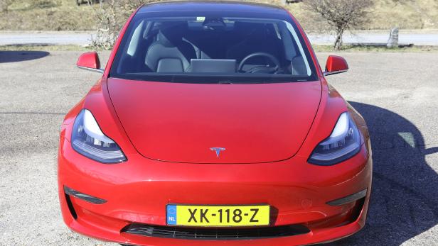 Ein rotes Tesla Model 3 mit niederländischem Kennzeichen steht geparkt.