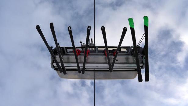 Ein Sessellift mit Skiern vor einem bewölkten Himmel.