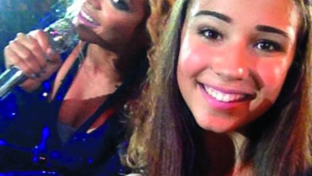 Eine junge Frau macht ein Selfie mit Beyoncé, die ein Mikrofon hält.