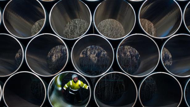 Ein Bauarbeiter mit Schutzhelm inspiziert das Innere eines großen Rohres.