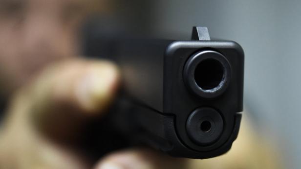 Eine Person zielt mit einer schwarzen Pistole.