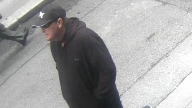 Ein Mann mit einer New York Yankees-Kappe und Sonnenbrille geht die Straße entlang.