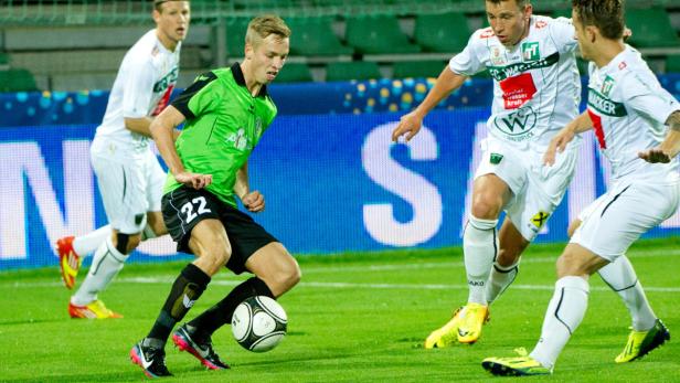Ein Fußballspieler in Grün dribbelt den Ball während eines Spiels.