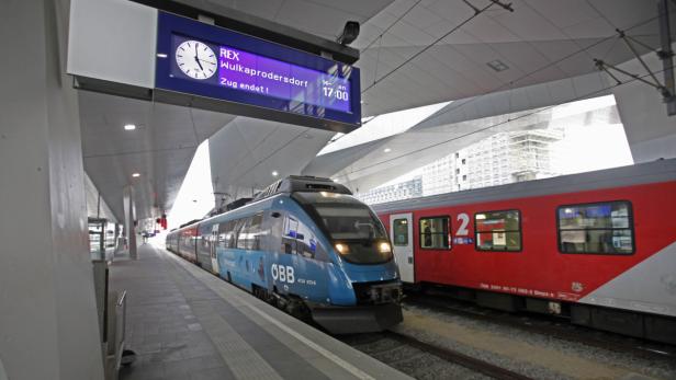 Ein blauer ÖBB-Zug steht am Bahnsteig in einem Bahnhof.
