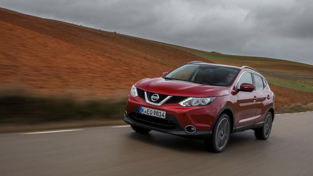 Ein roter Nissan Qashqai fährt auf einer Landstraße.