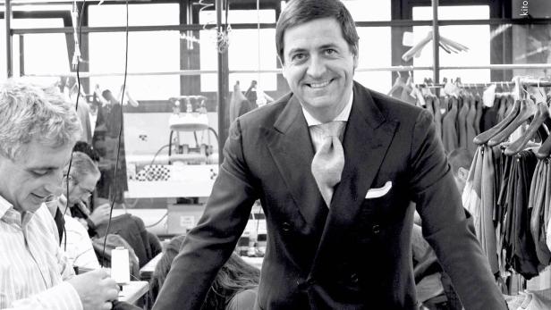 Ein lächelnder Mann im Anzug steht in einer Schneiderei.