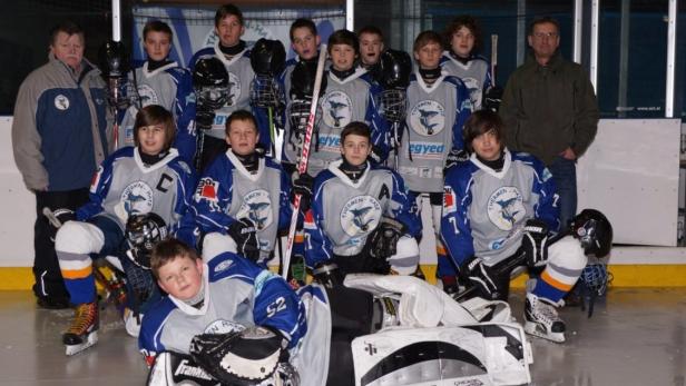Eine Jugend-Eishockeymannschaft posiert für ein Gruppenfoto auf dem Eis.