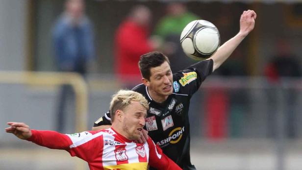 Zwei Fußballspieler kämpfen um den Ball.