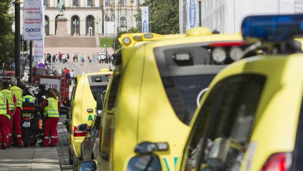 Gelbe Krankenwagen stehen in einer Reihe vor einem Gebäude mit Menschenmenge.