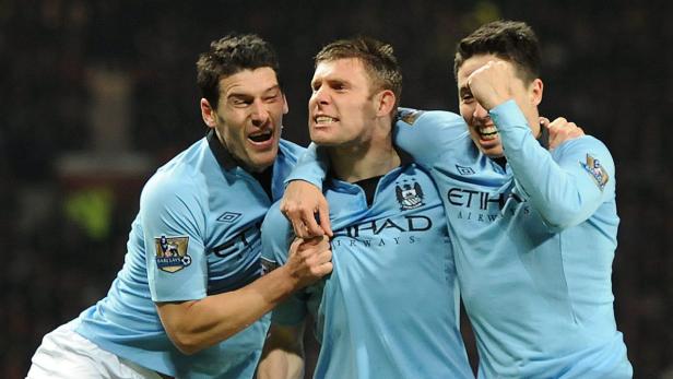 Drei Fußballspieler von Manchester City feiern ein Tor.