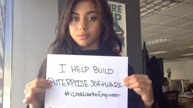 Eine Frau hält ein Schild mit der Aufschrift „I HELP BUILD ENTERPRISE SOFTWARE. #iLookLikeAnEngineer“.