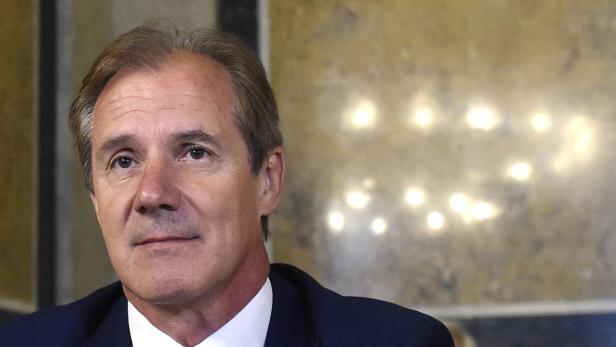 Ein Mann im Anzug vor einem unscharfen Hintergrund.