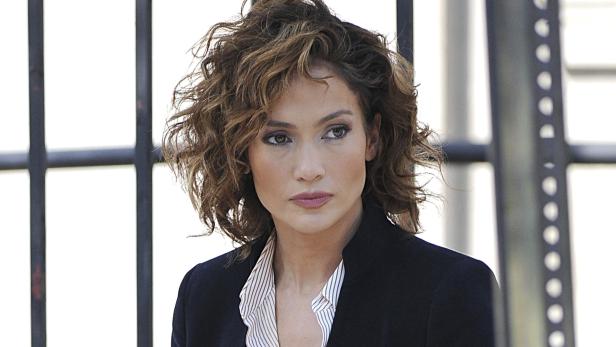 Jennifer Lopez mit lockigem Haar und einem gestreiften Hemd unter einem schwarzen Blazer.