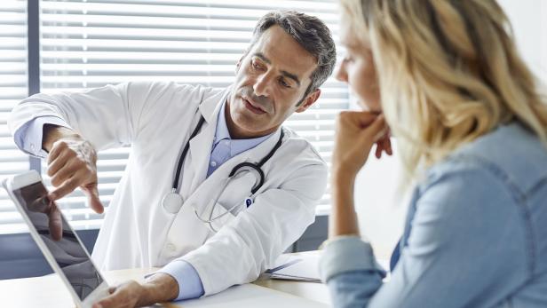 Doctor showing digital tablet to woman in hospital