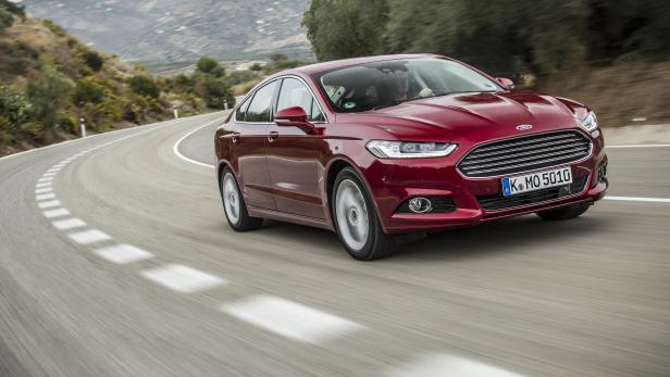 Ein roter Ford Mondeo fährt auf einer kurvenreichen Straße.