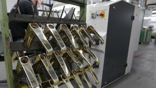 An employee works on plumbing equipment at the polishing stage of the assembly line of bathroom and sanitation company Hansgrohe, in Schiltach, Southwestern Germany