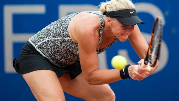 Eine Tennisspielerin schlägt einen gelben Tennisball.