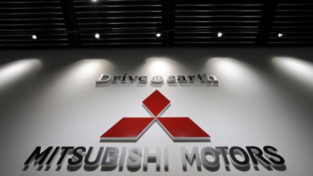 Das Mitsubishi Motors Logo an einer Wand mit dem Slogan „Drive @ earth“ darüber.