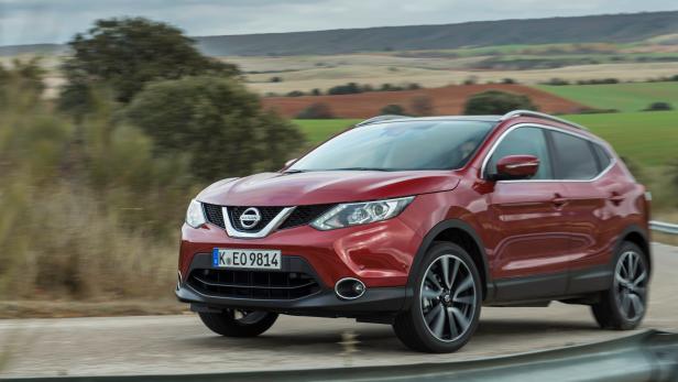 Ein roter Nissan Qashqai fährt auf einer Landstraße.