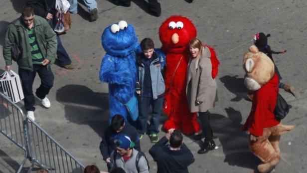 People pose for photos with characters dressed up as Elmo and Cookie Monster in Times Square in New York, March 30, 2013. REUTERS/Carlo Allegri (UNITED STATES - Tags: SOCIETY)