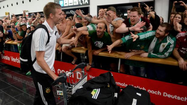 Ein Fußballspieler wird am Flughafen von Fans begrüßt.