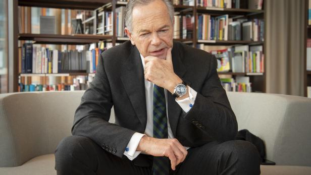 Andreas Treichl sitzt nachdenklich auf einem Sofa vor einem Bücherregal.